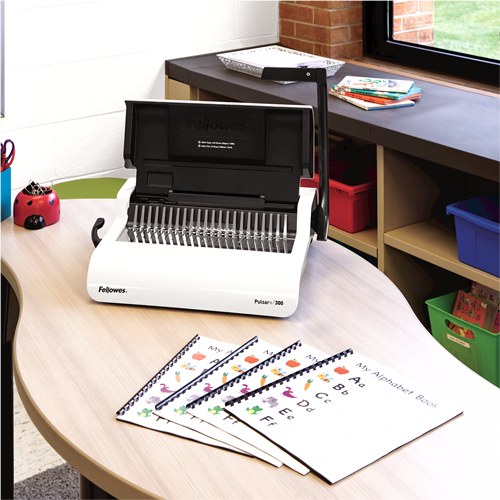 Pulsar+ 300 on a curved office desk beside a set of comb bound alphabet booklets, shelves and plants behind