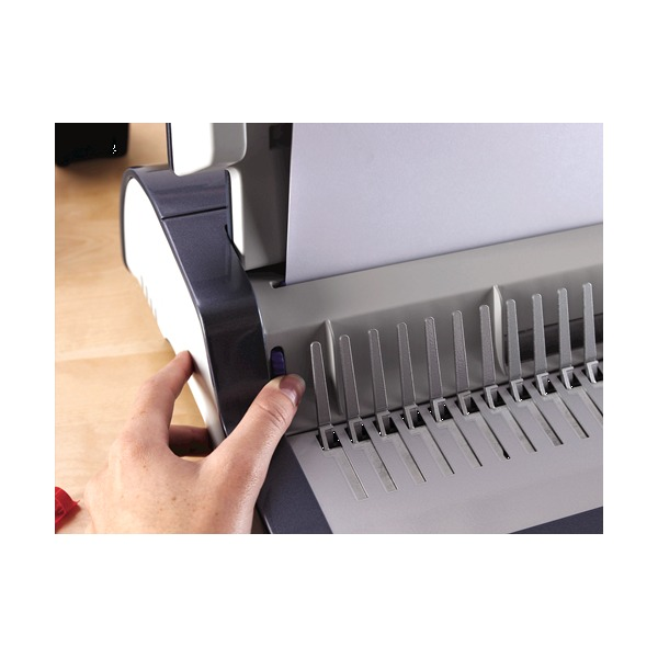 Hand at the side of the Quasar-E 500 next to a blue switch while paper stands in the punch slot