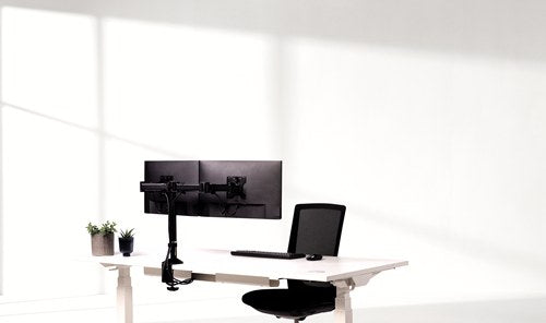 White desk with two screens on a black Fellowes Reflex dual arm, an office chair and two pot plants