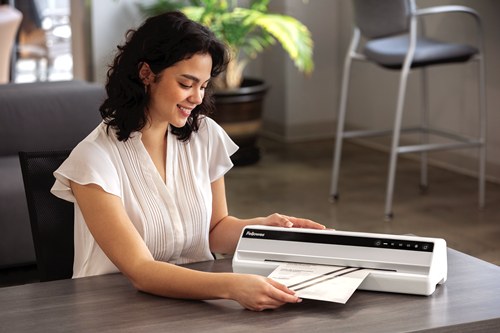 Woman feeding a cleaning sheet through a white Fellowes Saturn A3 laminator on a desk