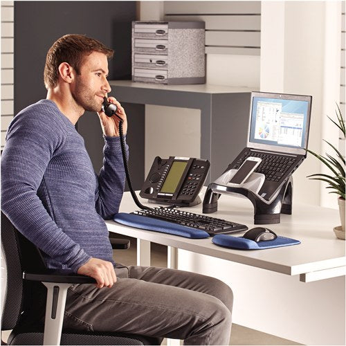 Man on the phone at an office desk with his laptop raised on the Smart Suites laptop riser