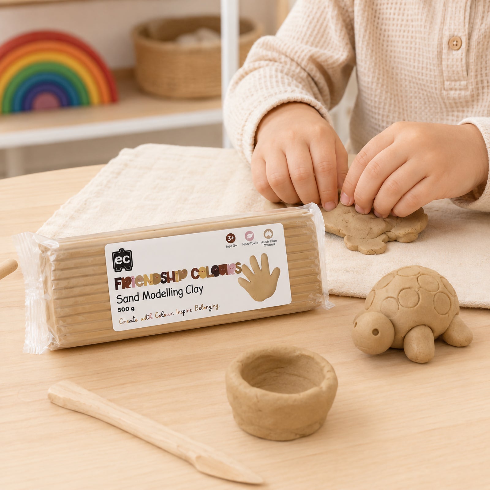 Educational Colours Friendship Colours Sand Modelling Clay 500g displayed beside a child creating clay shapes and sculptures. The warm sand coloured clay demonstrates its soft texture and flexibility, making it ideal for inclusive classroom projects, sensory learning activities and creative sculpting experiences.