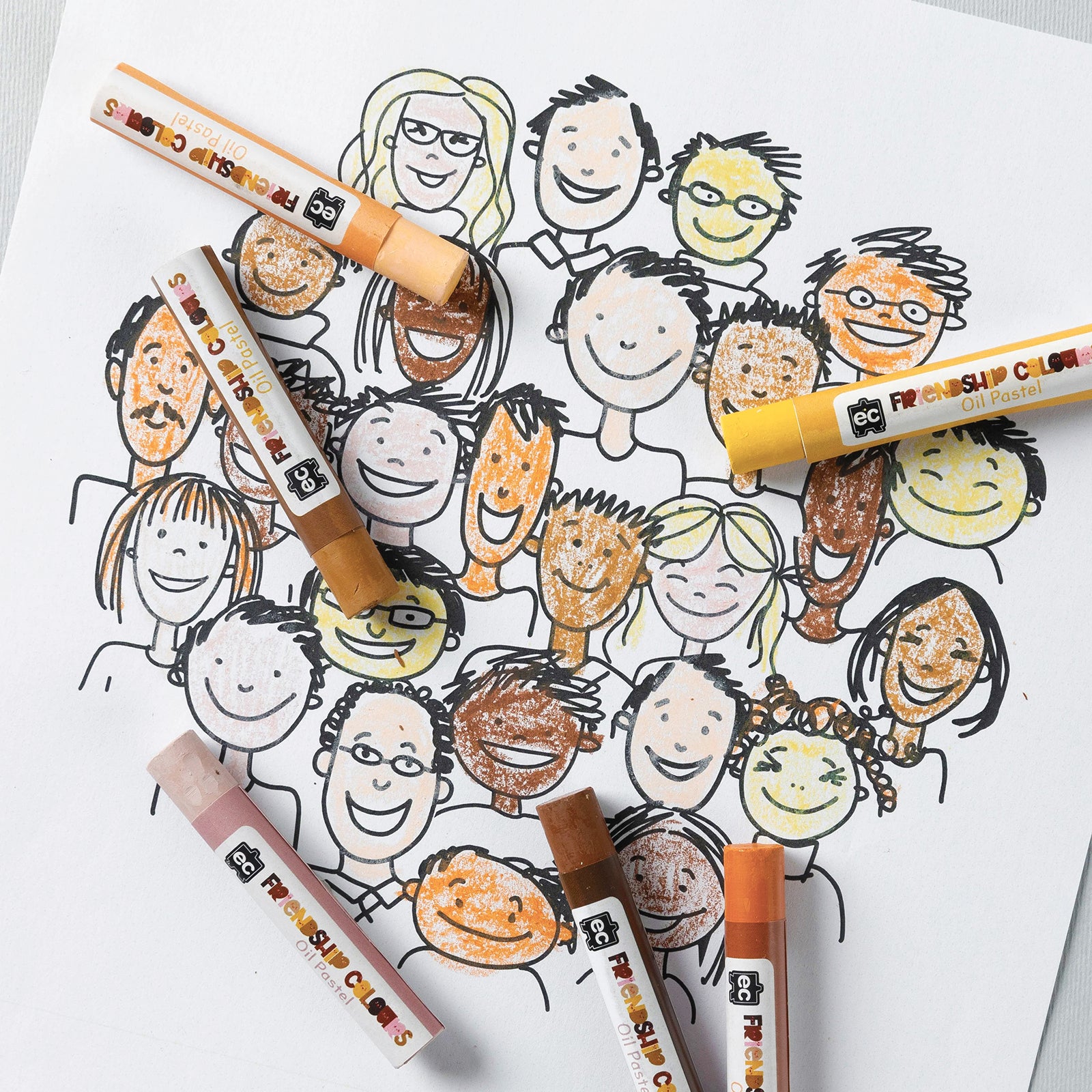 Close up view of Friendship Colours Oil Pastels placed across a community themed portrait page. Various skin tone colours have been used to colour faces and characters, highlighting the pastel set's suitability for diversity focused classroom activities and portrait drawing projects.