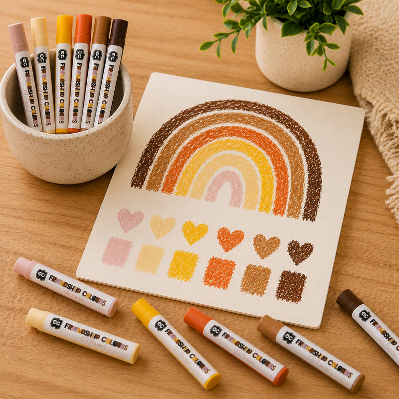 Friendship Colours Oil Pastels arranged around an artwork showing blended rainbow arches and colour swatches. The image highlights the pastel range, blending capabilities and warm skin tone inspired palette suitable for portrait work, shading exercises and inclusive art projects.