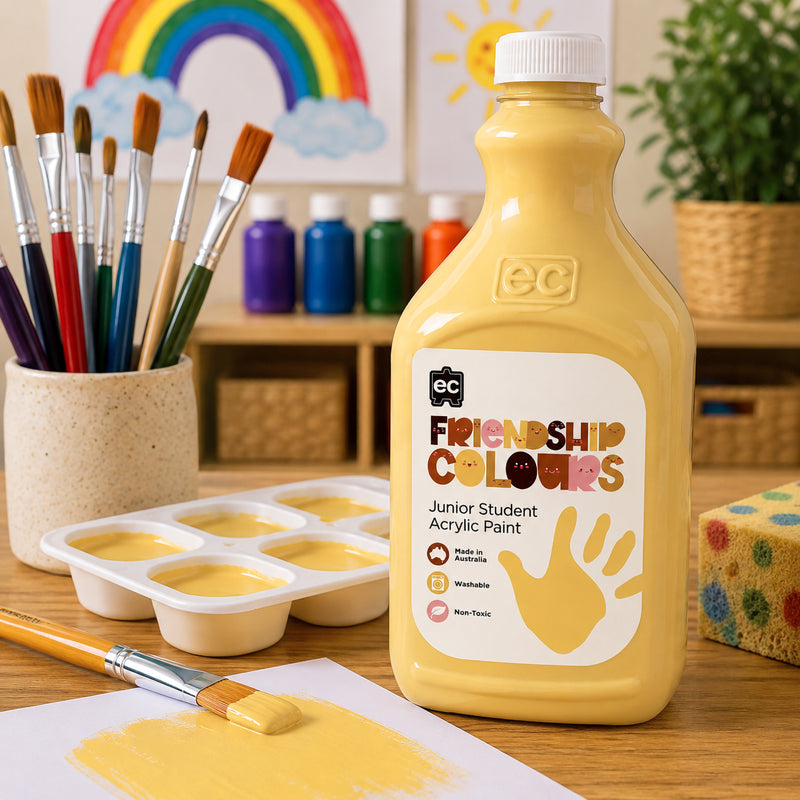 Educational Colours Friendship Colours Sand Acrylic Paint 2L displayed on a classroom art table beside paint brushes, paint trays and a warm sand coloured paint sample. Rainbow artwork, colourful paint bottles and creative classroom resources create an inviting environment focused on inclusive learning and artistic expression.