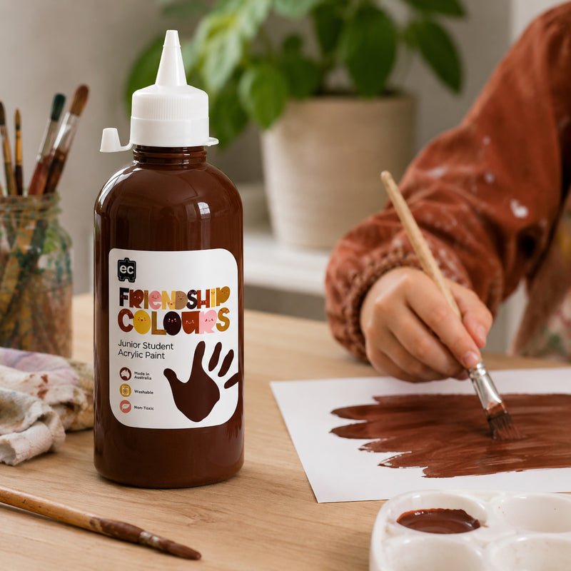 Educational Colours Friendship Colours Espresso Acrylic Paint 500ml displayed on an art table beside a child painting with a brush. The rich espresso brown paint is spread across white paper, highlighting its suitability for portrait work, diversity projects and inclusive classroom art activities.
