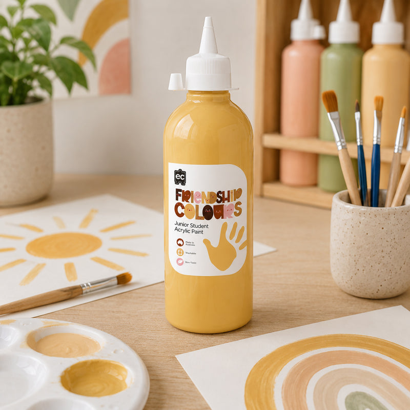 Friendship Colours Sand Paint bottle positioned in a bright art space surrounded by paint brushes, colour samples and educational art displays. The warm skin tone shade demonstrates how the paint supports diversity themed projects, self portraits and multicultural creative expression.