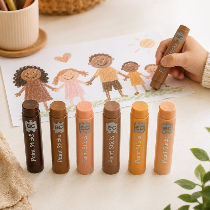 Six paint sticks displayed in front of a completed drawing showing children of different backgrounds holding hands outdoors. A child uses one paint stick to add details, illustrating diversity, friendship, belonging and creative storytelling through art.
