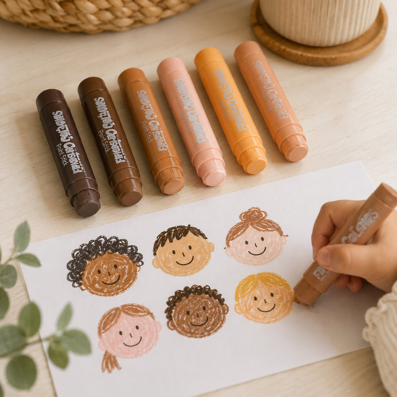 Friendship Colours Paint Sticks arranged above a sheet featuring hand drawn portraits created in diverse skin tones. A child colours one of the illustrations, demonstrating how the paint sticks support identity exploration, portrait drawing and inclusive classroom art projects.