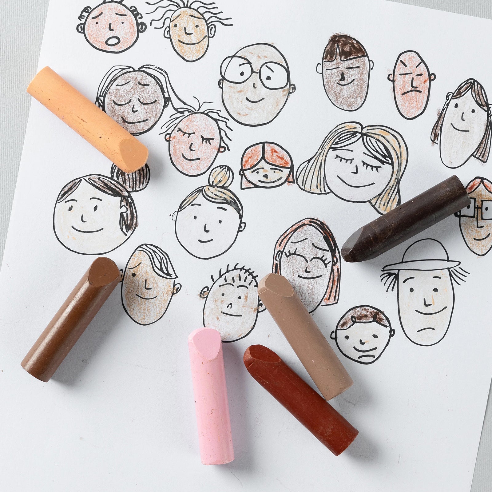 Various facial illustrations coloured using the Friendship Colours Stubby Crayons demonstrate how children can represent different skin tones and identities through drawing and creative self expression.