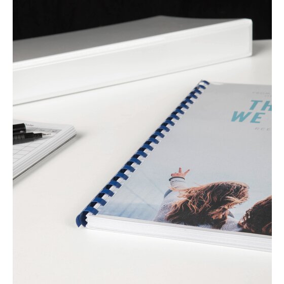 A4 document with a blue plastic comb spine lying on a desk, its cover showing a photo of two people outdoors