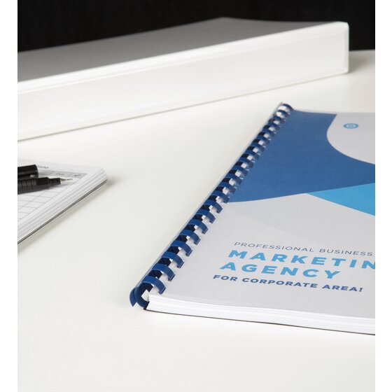 Marketing report bound with a blue plastic comb lying on a white desk, a notepad and pens to the left