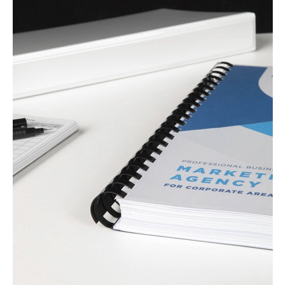 Thick report with a blue and white cover bound on a wide black GBC plastic comb, on a white desk beside a folder and pens