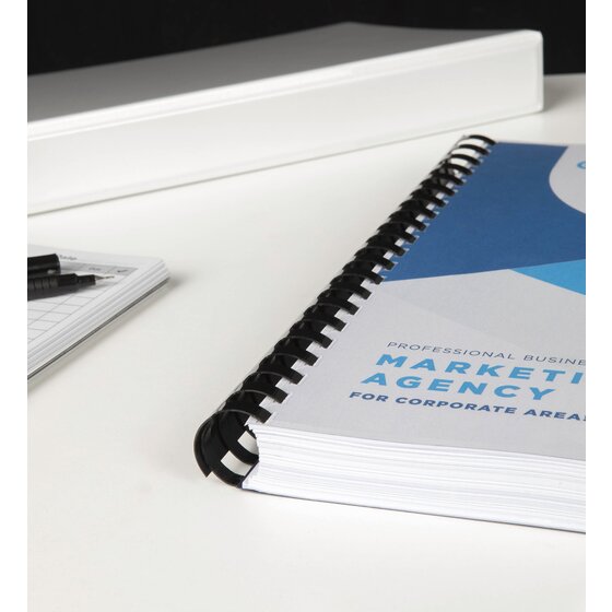 Thick booklet with a Marketing Agency cover bound on a black GBC plastic comb, lying on a white desk