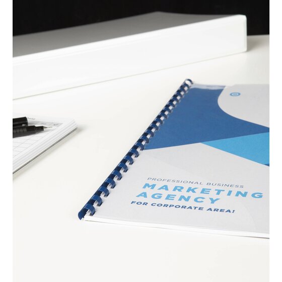 Marketing document bound with a blue plastic comb lying on a white desk, a white ring binder and a notepad behind it
