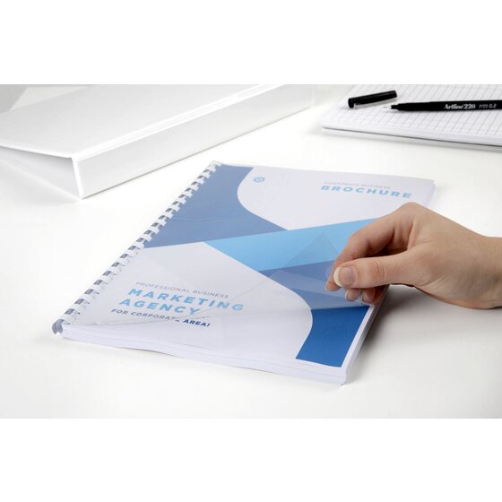 Clear front cover lifted by hand from a brochure bound with a white plastic comb, the printed title page showing through