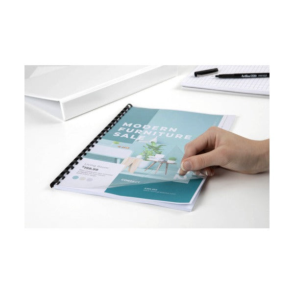 Hand lifting a clear front cover on a furniture sale catalogue bound with a black plastic comb