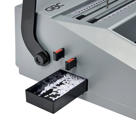 Close view of the side of the GBC MB20 with its pull out black clippings tray filled with punched paper chips