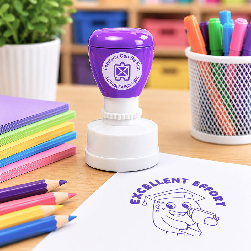 Close up classroom scene featuring the purple self inking merit stamp surrounded by coloured pencils, craft paper and learning resources. The stamped Excellent Effort image demonstrates the large, easy to read impression suitable for worksheets, homework and student projects.
