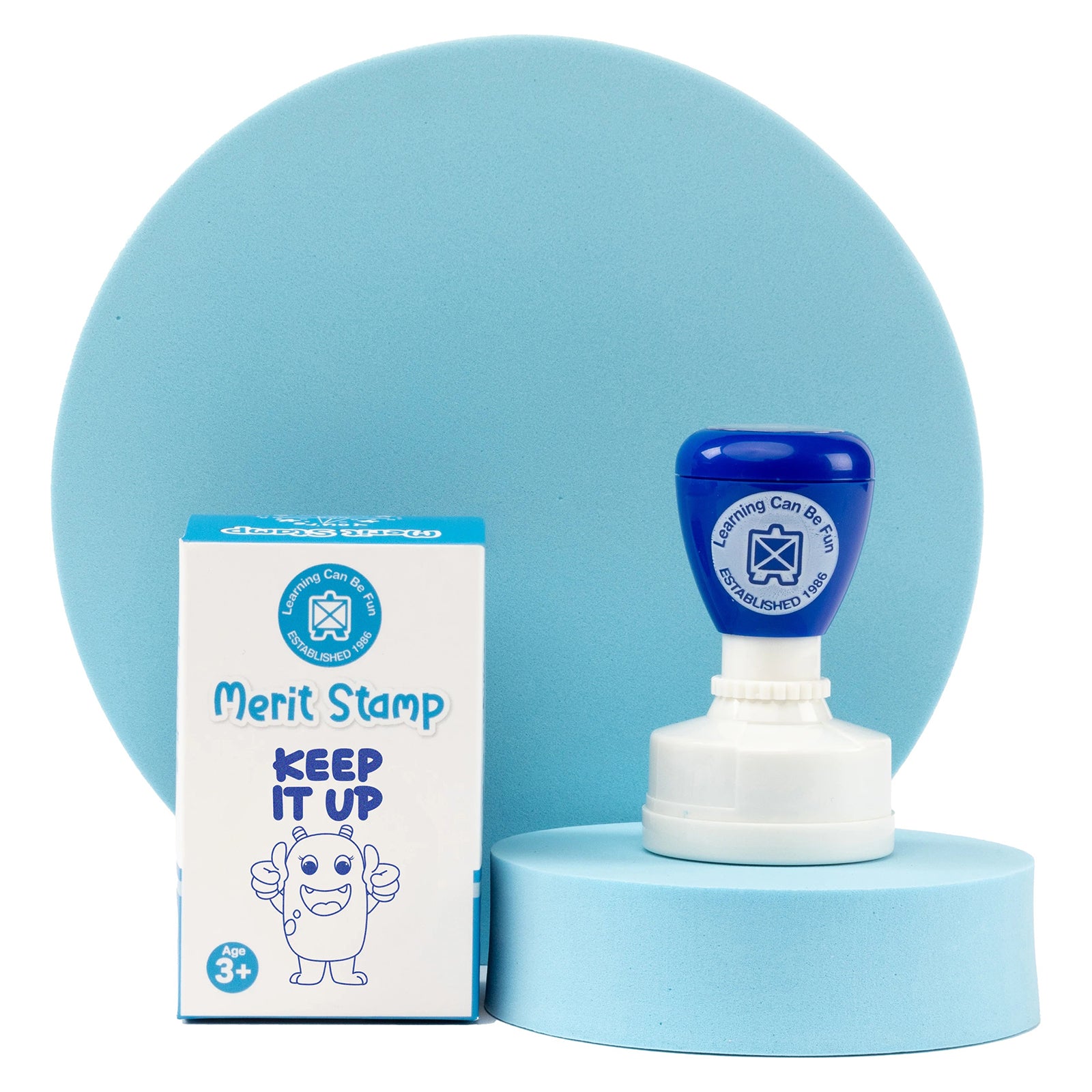 Retail packaging and self inking merit stamp displayed against a soft blue backdrop. The packaging clearly presents the Keep It Up theme while highlighting the compact stamp design created for rewarding persistence and motivating young learners.