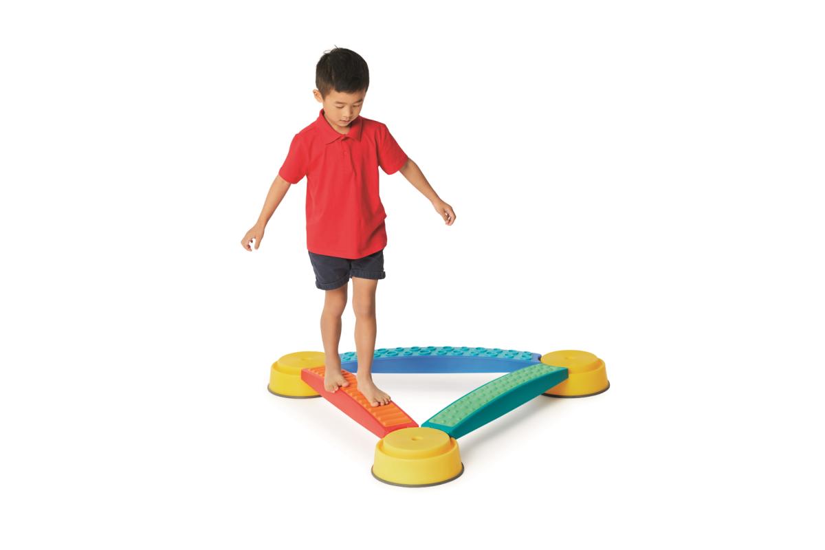 Boy walking barefoot on the orange Gonge Tactile Plank in a triangle course set between yellow Build N' Balance tops, sold separately