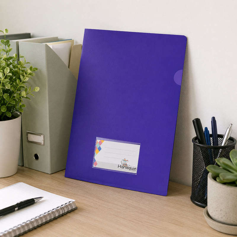Harlequin purple letter file standing upright against a wall on a tidy office desk beside magazine files, stationery holders and indoor plants. The lifestyle setting showcases the slim profile, card pocket and professional filing solution for desktop organisation.