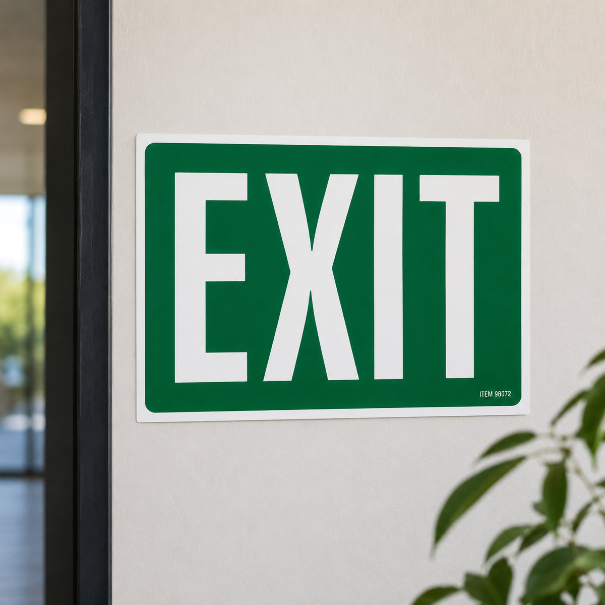 Close up front view of the Headline Exit Sign installed on an interior wall beside a doorway. The bold white EXIT lettering on the green background is highly visible, demonstrating its suitability for office, retail and public building safety signage.