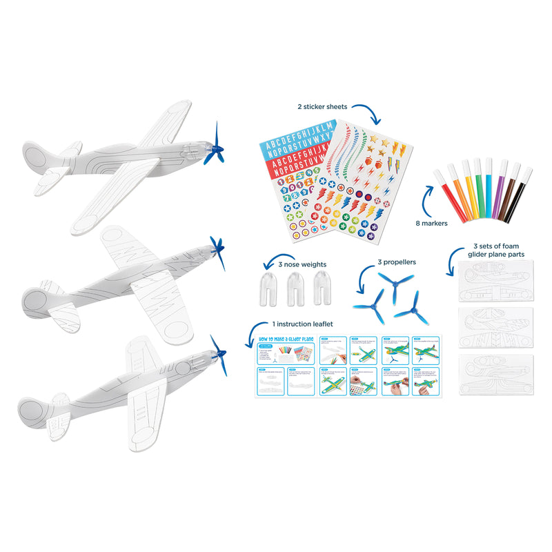 Flat lay presentation of the complete kit contents including foam plane parts, coloured markers, sticker sheets, propellers, nose weights and instruction leaflet. The layout clearly shows everything required to create three personalised gliders.