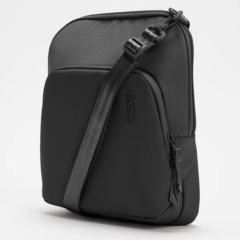 Three quarter angled studio photograph of the Incase A.R.C. Crossbody Bag highlighting the structured silhouette, smooth front device pocket, textured recycled polyester exterior, premium YKK zippers and adjustable shoulder strap. The perspective showcases the refined urban styling and compact proportions.