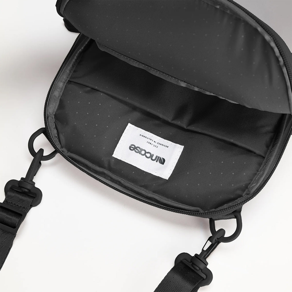 Close up view of the Incase A.R.C. Crossbody Bag with the main compartment fully open, revealing the premium interior lining, spacious storage cavity and quality stitched construction. The image highlights the durable recycled polyester interior and demonstrates the generous space available for organising everyday essentials.