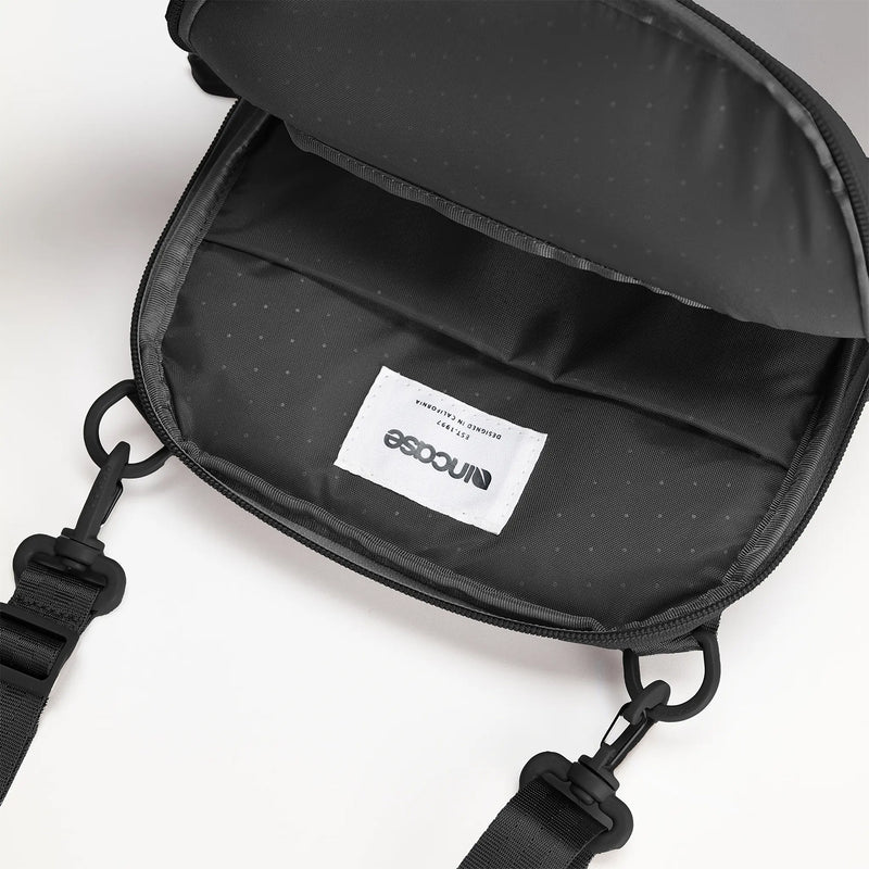 Close up view of the Incase A.R.C. Crossbody Bag with the main compartment fully open, revealing the premium interior lining, spacious storage cavity and quality stitched construction. The image highlights the durable recycled polyester interior and demonstrates the generous space available for organising everyday essentials.