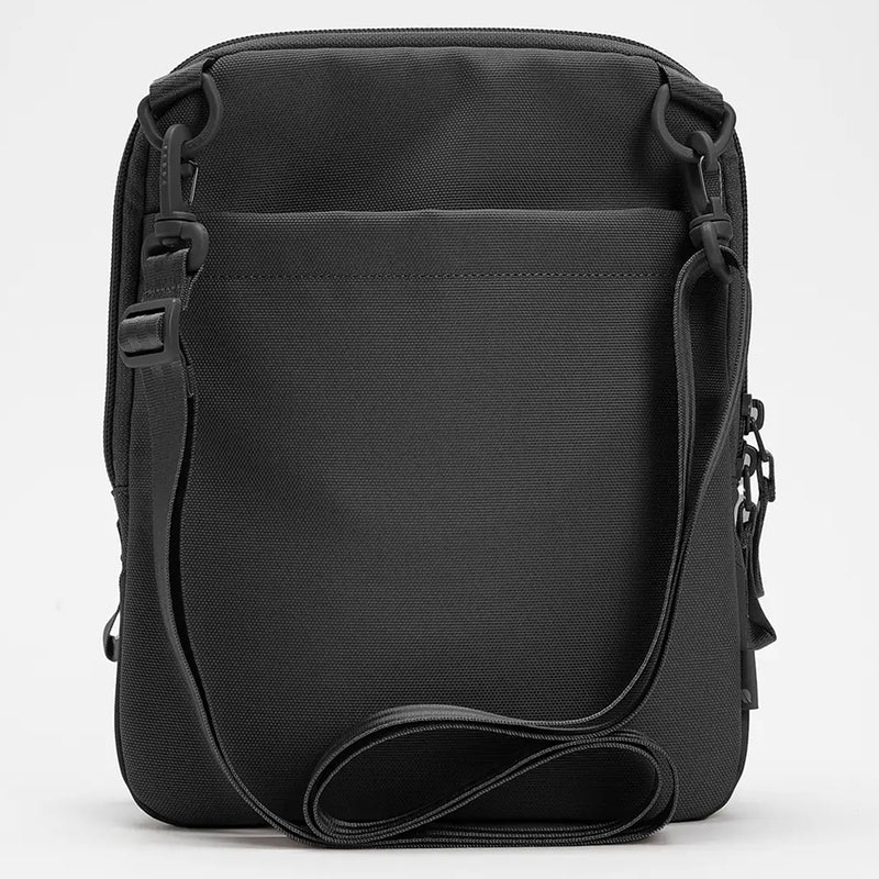 Rear view of the Incase A.R.C. Crossbody Bag showcasing the clean minimalist back panel, durable recycled polyester fabric, adjustable detachable shoulder strap and premium attachment hardware. The image demonstrates the sleek profile and practical everyday carry design from the back.