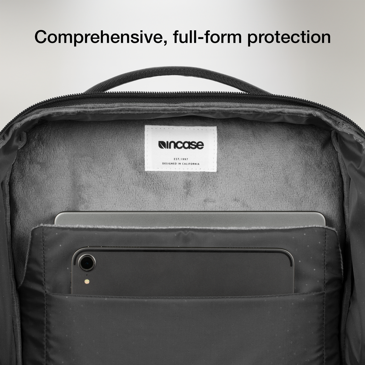 Open laptop compartment of the black Incase A.R.C. Daypack, showing the soft grey lining and a tablet in the front slip pocket