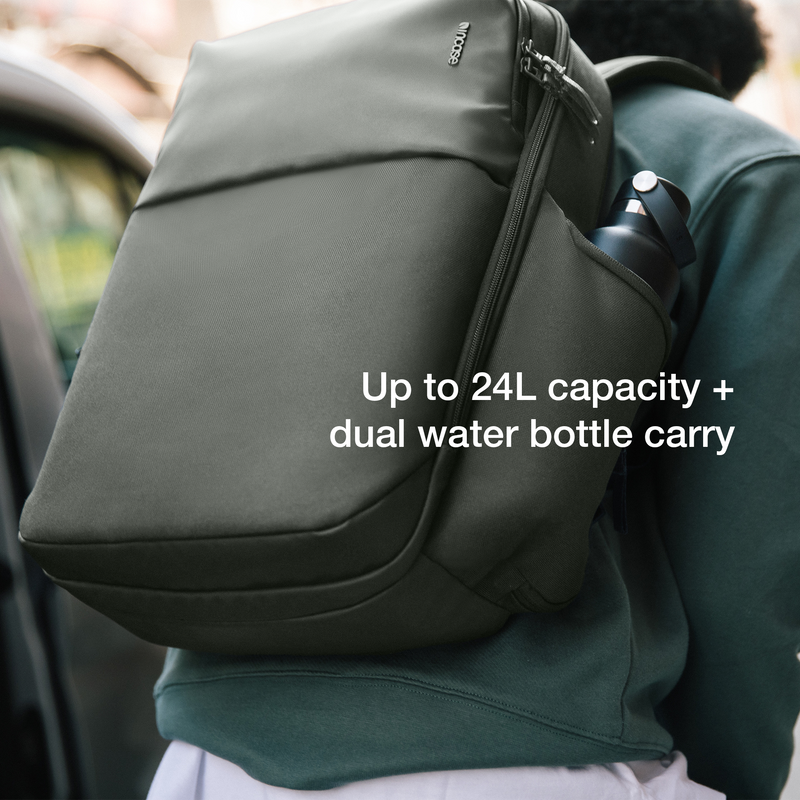 Smoked Ivy Incase A.R.C. Daypack worn on one shoulder with a water bottle in the side pocket, captioned Up to 24L capacity plus dual water bottle carry
