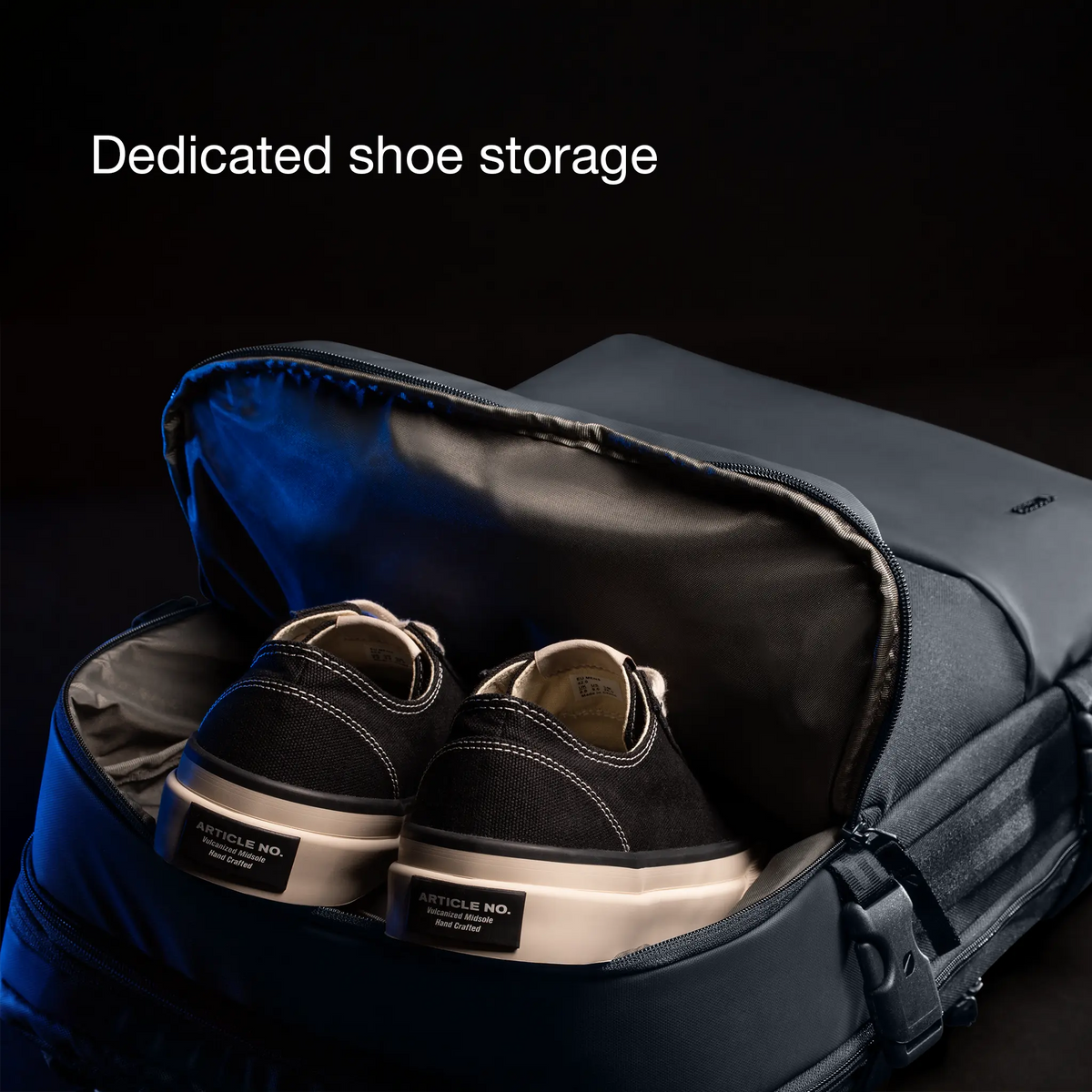 Shoe compartment of the Incase A.R.C. Travel Pack with a pair of sneakers inside, captioned Dedicated shoe storage