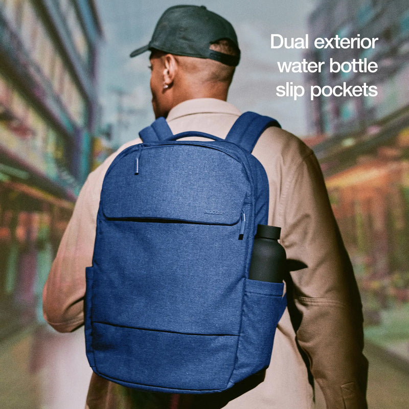 Model wearing the navy Crosstown Backpack with a bottle in the side pocket, with the caption Dual exterior water bottle slip pockets