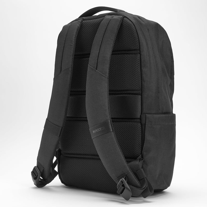 Rear angled product view illustrating the ergonomic shoulder straps, padded back construction and side profile while maintaining a clean minimalist aesthetic.