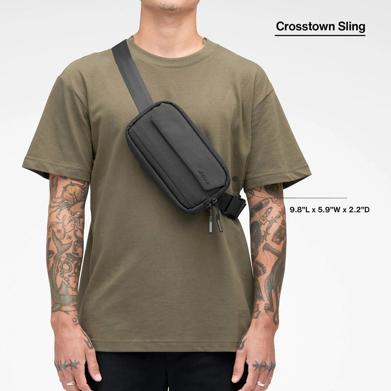 Front model view showing the Incase Crosstown Sling Black worn diagonally across the torso. Dimension graphics illustrate the compact size of approximately 9.8 inches long, 5.9 inches wide and 2.2 inches deep.