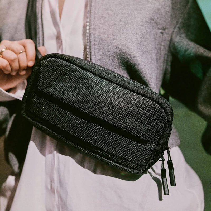 Lifestyle close up of the Incase Crosstown Sling Black being worn across the body in an indoor setting. The image demonstrates comfortable crossbody positioning, premium fabric texture and compact size for everyday use.
