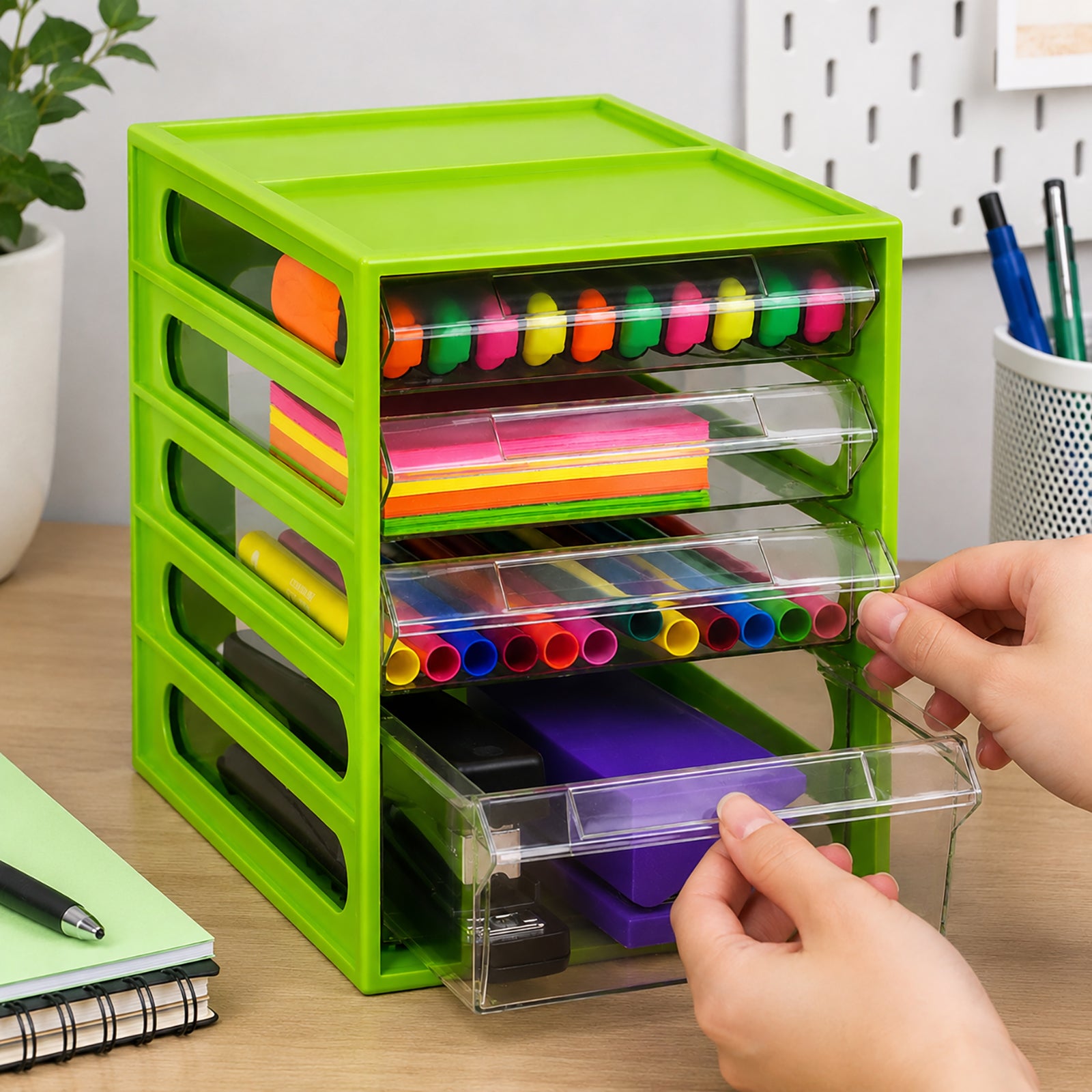 Italplast 4 Drawer Office Organiser in bright Lime positioned on a timber desk with clear drawers containing colourful highlighters, sticky notes, writing tools and stapling equipment. Hands pull open the lower compartments to demonstrate convenient access, while notebooks and desk accessories show how the organiser can support an efficient everyday workspace.