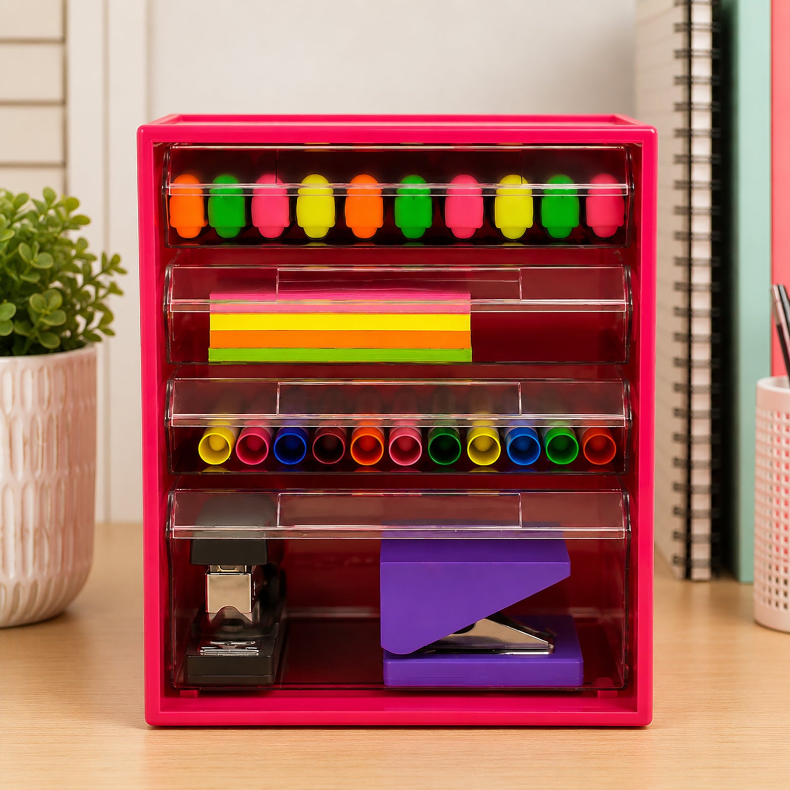 Front view of the Watermelon Italplast 4 Drawer Office Organiser showing the clear compartment layout filled with highlighters, coloured sticky notes, pens and larger stapling equipment. The transparent drawers provide immediate visibility of supplies while the bright frame creates a colourful storage solution for office, classroom or study use.
