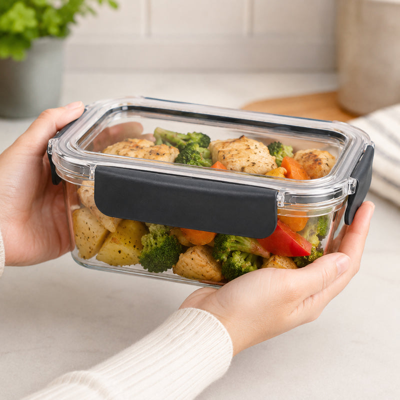 Italplast 1300ml clear Snap Lock Food Container held securely in two hands and filled with cooked chicken, broccoli, carrots and other vegetables. The close kitchen setting highlights the compact rectangular shape, transparent body and lid, and dark snap lock closures, showing how the container can be used for prepared lunches and individual meal portions.