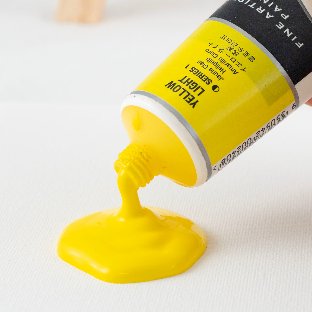 Close up of Yellow Light pouring from the tube onto canvas, barcode visible on the tube