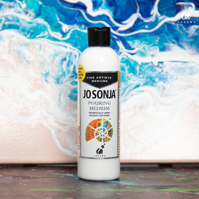 Jo Sonja Pouring Medium bottle standing in front of a blue, white and peach acrylic pour painting with flowing cells