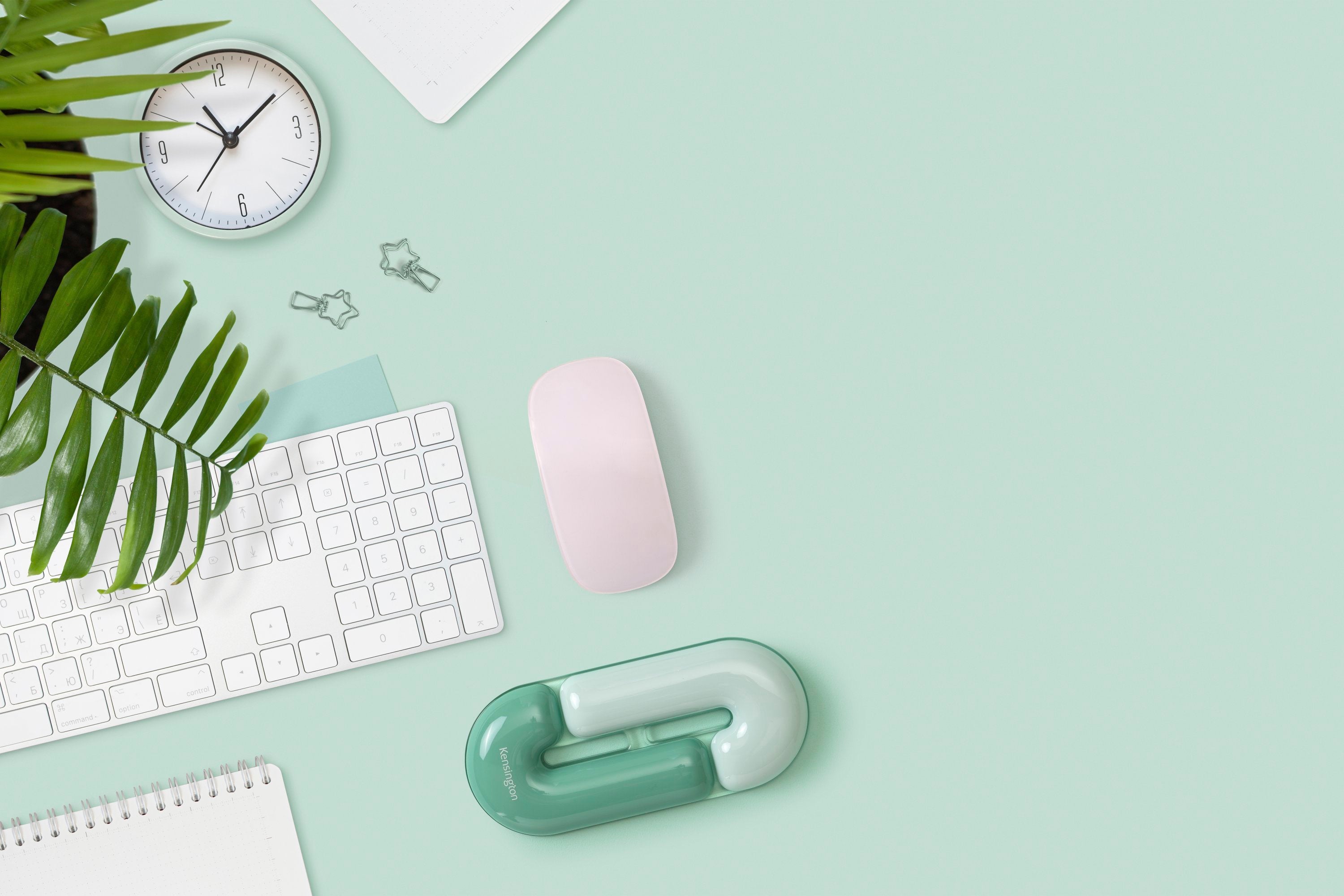 Desk setup with keyboard, mouse, and decorative items on a light green surface