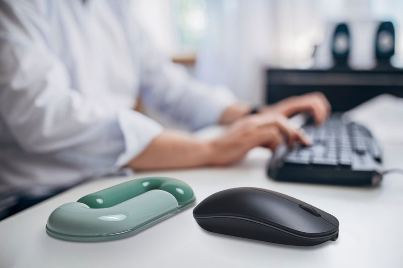 Two computer mice on a desk with a person using a keyboard in the background.
