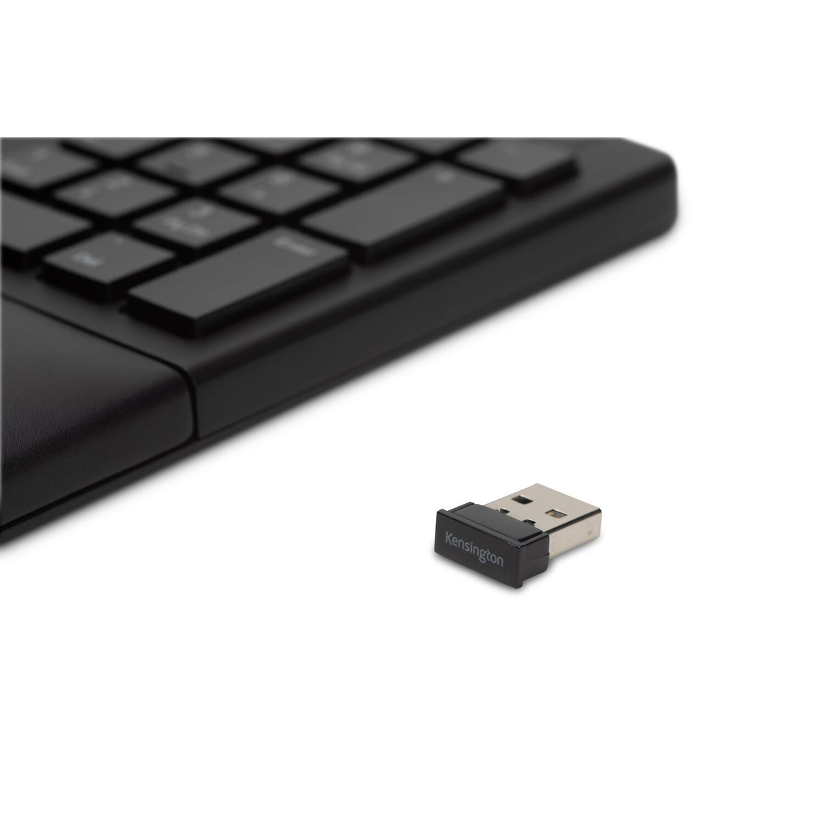 Kensington replacement USB nano receiver lying beside the corner of a black wireless keyboard