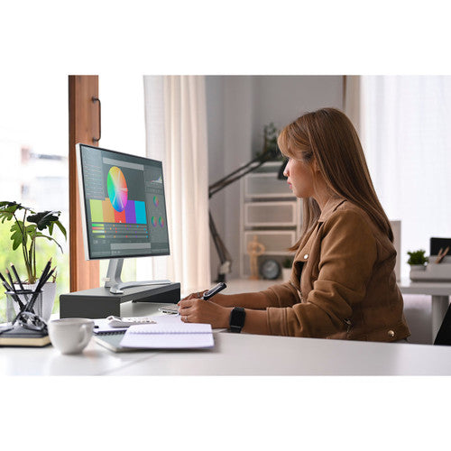 Person working at a desk with a monitor raised on the black Kensington extra wide steel monitor stand