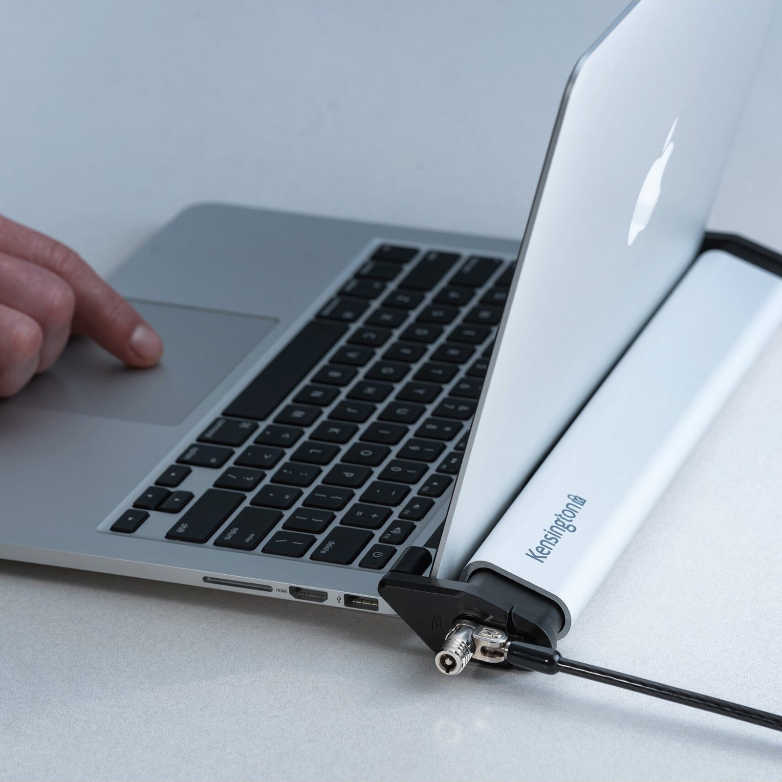 Detailed view showing the locking station holding a laptop securely in place while maintaining access to ports and controls. The image demonstrates the non invasive design that protects the device without requiring modifications.