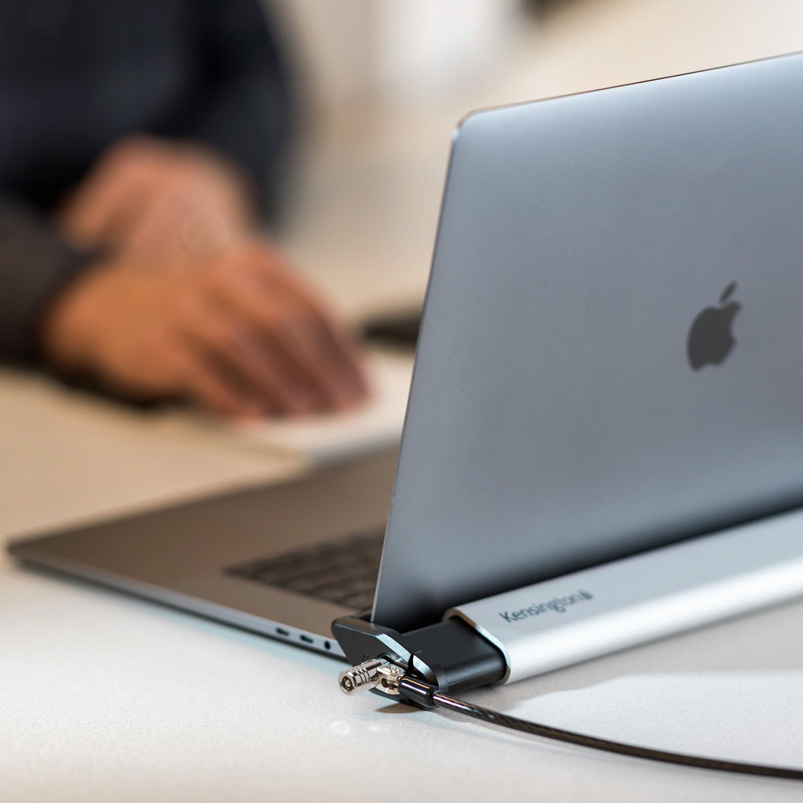 Close up side view of a MacBook secured inside the Kensington Locking Station. The image highlights the sleek brushed aluminium construction, secure cable attachment and premium design that complements modern laptops.